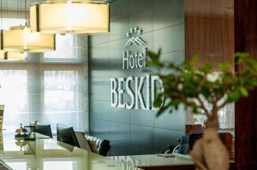 a hotel desk with a sign on a wall at Hotel Beskid in Nowy Sącz