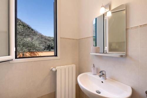 Un baño con lavabo y ventana. en Appartamento Ferla La Taggiasca, en Stellanello