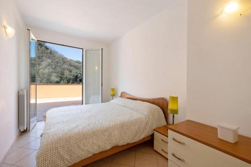 Un dormitorio con una cama y una ventana grande. en Appartamento Ferla La Taggiasca, en Stellanello
