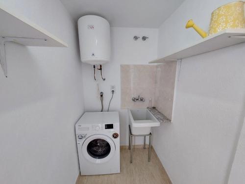 uma lavandaria com uma máquina de lavar roupa e um lavatório em Mar i Angels Apartament em Pineda de Mar