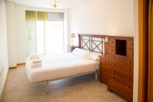 a bedroom with a bed and a dresser and a window at Apartamento Welcome Portonovo Playa in Sanxenxo