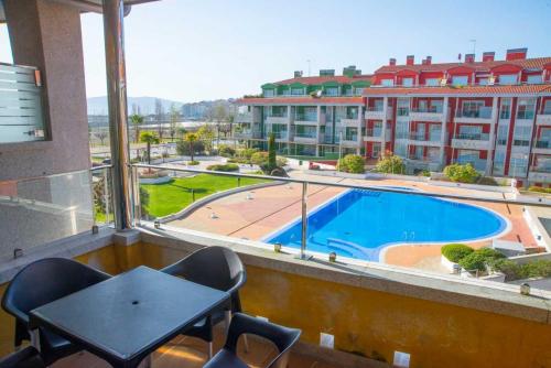 a balcony with a table and chairs and a swimming pool at Apartamento Welcome Portonovo Playa in Sanxenxo