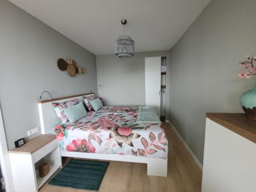 a small bedroom with a bed with pink flowers at Zeesterflat 117 in Egmond aan Zee