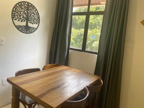 einen Holztisch und Stühle in einem Zimmer mit Fenster in der Unterkunft Kitnet Beira Rio in Alfredo Wagner