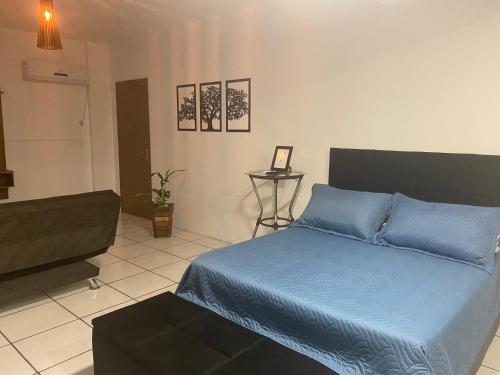a bedroom with a blue bed and a couch at Kitnet Beira Rio in Alfredo Wagner