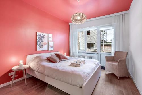 1 dormitorio con paredes rosas, 1 cama y 1 silla en Ruim, rustgevend glv app met warme kleuraccenten en Middelkerke