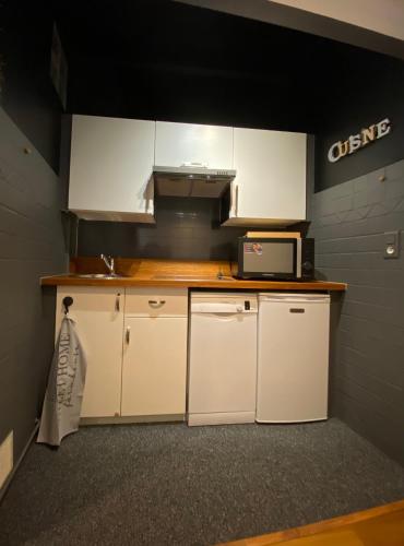 une petite cuisine avec des armoires blanches et un micro-ondes dans l'établissement Superbe T2 à 150m des plages de Juan les Pins, à Juan-les-Pins