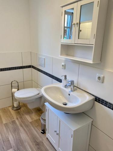 a white bathroom with a sink and a toilet at Ferienwohnung Hof Falke in Suderbruch