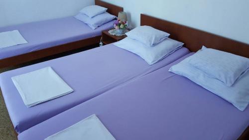 2 Betten in einem Zimmer mit lila Bettwäsche und Kissen in der Unterkunft Rooms Milena in Lopud Island