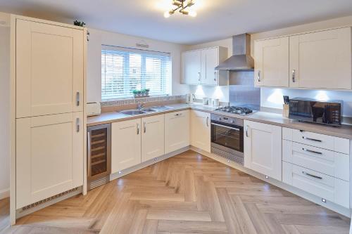 a kitchen with white cabinets and a wooden floor at Host & Stay - Redsky House in Whitby