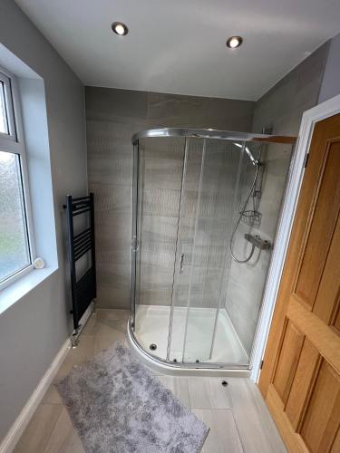 a shower with a glass door in a bathroom at The Homestead House in Doncaster