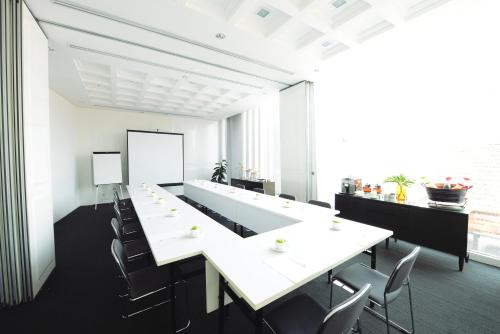 a conference room with a long white table and chairs at Morrissey Hotel in Jakarta