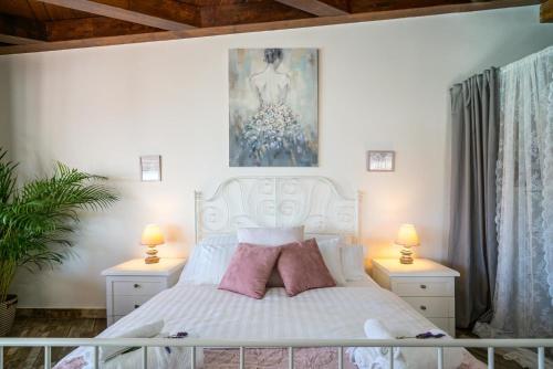 een slaapkamer met een wit bed met roze kussens bij Poolhaus Sicilysun Holidays Giulia in Letojanni