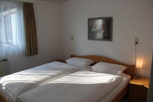 Schlafzimmer mit einem Bett mit weißer Bettwäsche und einem Fenster in der Unterkunft Hotel Restaurant Siegblick in Siegburg