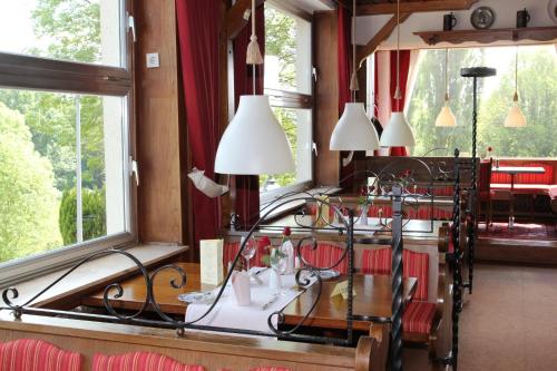 uma sala de jantar com mesa, cadeiras e janelas em Hotel Restaurant Siegblick em Siegburg