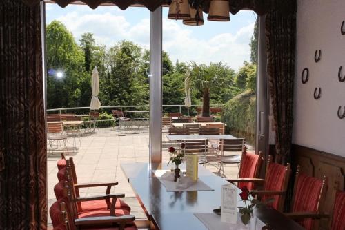 ein Restaurant mit einem Tisch und Stühlen sowie einem großen Fenster in der Unterkunft Hotel Restaurant Siegblick in Siegburg