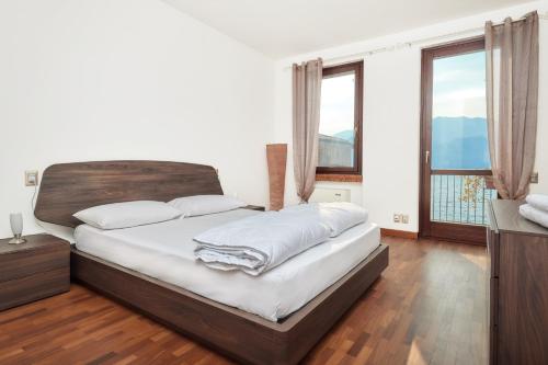 una camera da letto con letto, lenzuola bianche e finestre di Lake Front Casa Christina a Malcesine