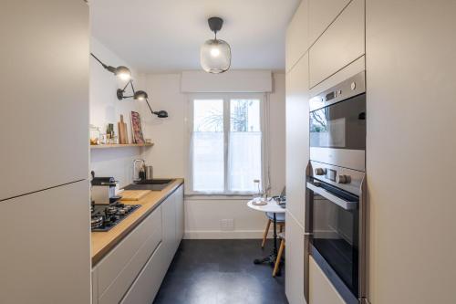 une cuisine avec un évier et une cuisinière four supérieur dans l'établissement LE SÉVIGNÉ - Appartement cocooning à proximité du Thabor, à Rennes