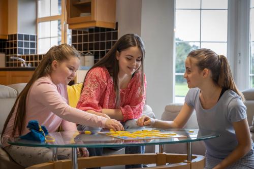 three girls sitting around a table playing a game at Gleneagle River Apartments in Killarney