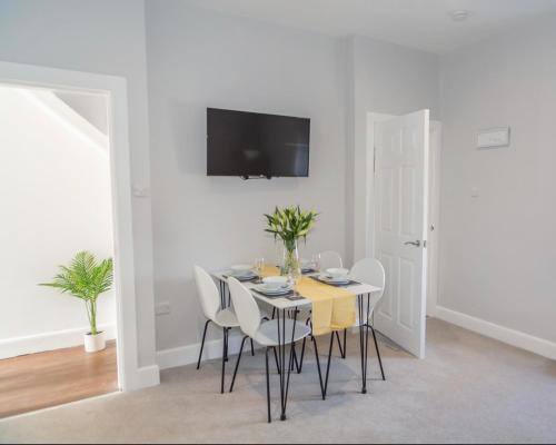a white dining room with a table and chairs at The Mila - Ayr Racecourse - Coorie Doon Stays in Ayr