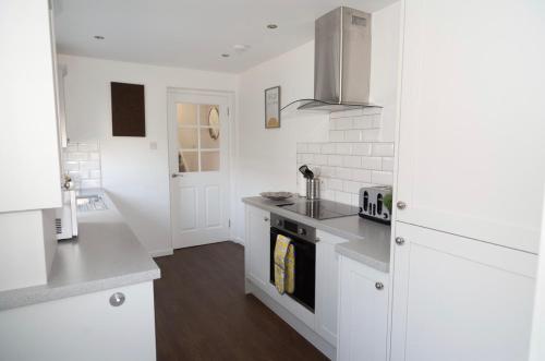 a kitchen with white cabinets and a stove top oven at The Mila - Ayr Racecourse - Coorie Doon Stays in Ayr