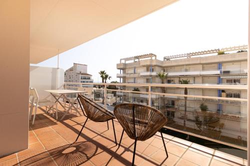 a balcony with chairs and a table and a building at Vista Roses Mar - Apartamento con piscina II in Roses