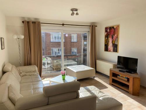 a living room with a couch and a television at Ruim zonnig appartement op 50m van strand in Ostend