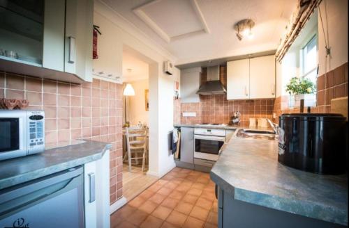 a kitchen with a counter top with a microwave at Dreamy Suffolk Country Cottage Escape in Aldeby