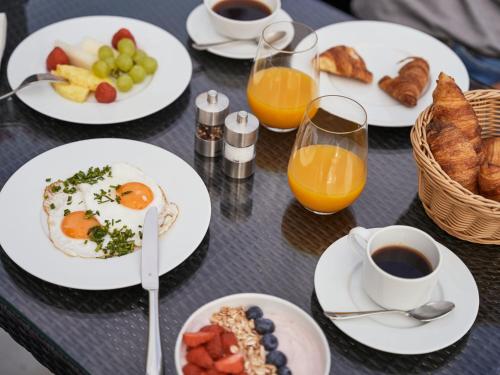 a table with plates of breakfast food and glasses of orange juice at A-ROSA Ostseehotel Kühlungsborn in Kühlungsborn