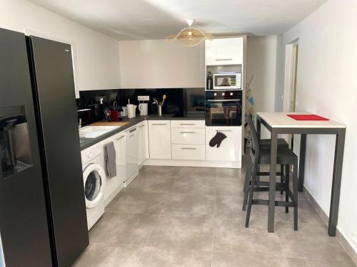 a kitchen with white cabinets and a table and a washer and dryer at Villa élégante Les Abymes, piscine in Baimbridge