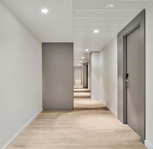an empty corridor of an office with white walls and wooden floors at Hostal Lami in Esplugues de Llobregat