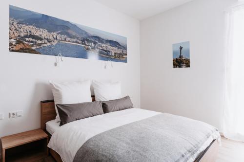 a white bedroom with a bed and a painting on the wall at STEP INN The Fair Hotel in Rosbach vor der Höhe