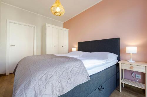 a bedroom with a bed and a night stand with a lamp at VacationClub - Let’s Sea Baltic Park B44 in Gąski