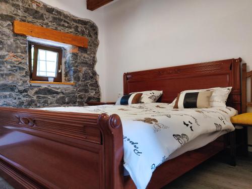 1 dormitorio con cama de madera y pared de piedra en Homestead Zavadlal - Domačija Zavadlal, en Komen
