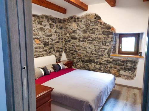 1 dormitorio con cama y pared de piedra en Homestead Zavadlal - Domačija Zavadlal, en Komen