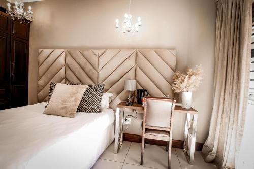 a bedroom with a bed and a desk and a chandelier at Potch Manor Boutique Guest House in Potchefstroom