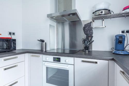 une cuisine avec des armoires blanches et un four à plaques de cuisson dans l'établissement L'Escale Marine, à Dunkerque