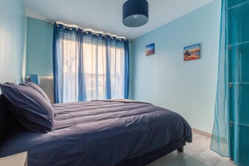 a bedroom with a bed with blue walls and a window at L'Escale Marine in Dunkerque
