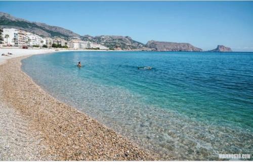 una persona parada en el agua en una playa en Piso Piteres 7 con piscina en Altea