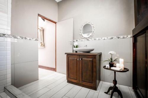 a bathroom with a sink and a mirror at Potch Manor Boutique Guest House in Potchefstroom