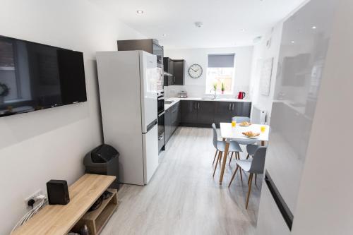 a kitchen with a white refrigerator and a table with chairs at Beamont House in Warrington