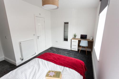 Schlafzimmer mit einem Bett mit einer roten Decke und einem Schreibtisch in der Unterkunft Beamont House in Warrington