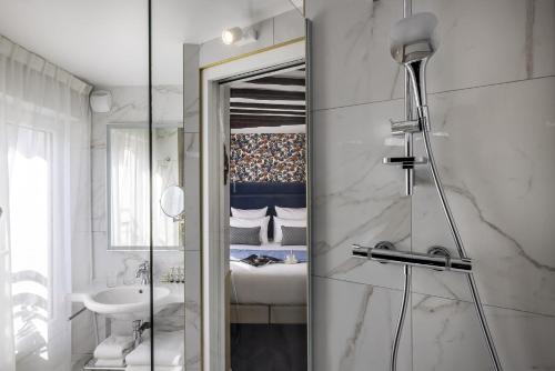 La salle de bains est pourvue d'une douche, d'un lavabo et d'un miroir. dans l'établissement Hotel Louis II, à Paris