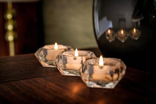 three candles sitting on top of a wooden table at Potch Manor Boutique Guest House in Potchefstroom