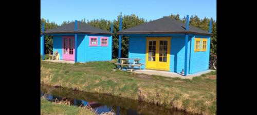 dwa kolorowe domy obok wody w obiekcie Camping de Oude Rijn w mieście Ter Aar