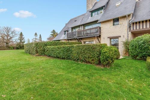 a house with a hedge in front of a yard at Nice flat in a beautiful estate 15 min by walk from Deauville - Welkeys in Tourgeville