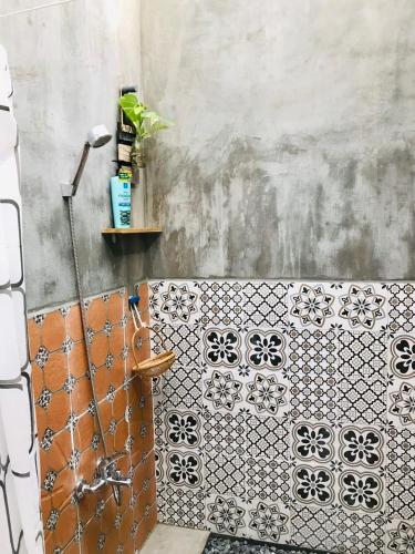 a bathroom with a tiled wall with a shelf at Green Sunshine Homestay in Can Tho