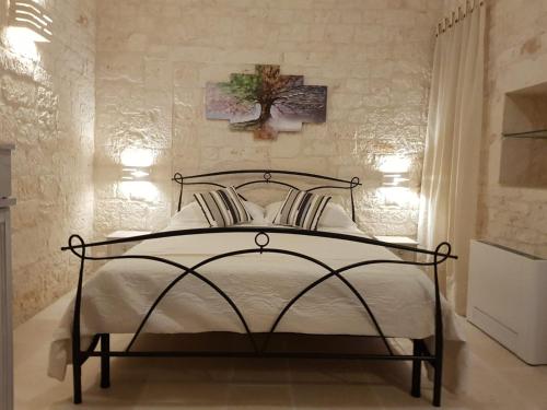 a bedroom with a bed with white sheets and a tree on the wall at Trulli stett in Cisternino