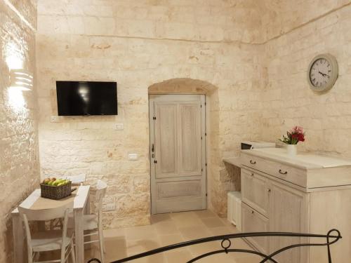 a kitchen with a table and a clock on the wall at Trulli stett in Cisternino