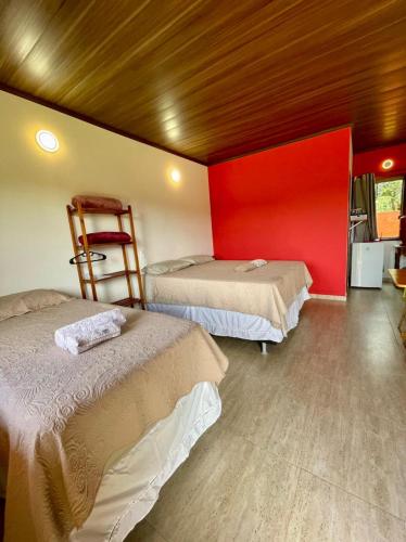 a room with two beds and a red wall at Água Doce Hospedagemw in Sao Jorge